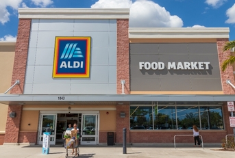 Aldi store front and shoppers coming out of it pushing a cart