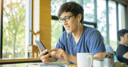Man at coffee shop with cell phone and earbuds