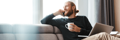 person relaxing on couch with phone and computer