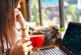 adult woman holding a coffee cup while looking at a stock chart on her laptop