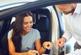 happy woman sitting in new car at car showroom signing papers