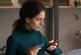 Focused young woman holding a smartphone in one hand and a card with another hand.