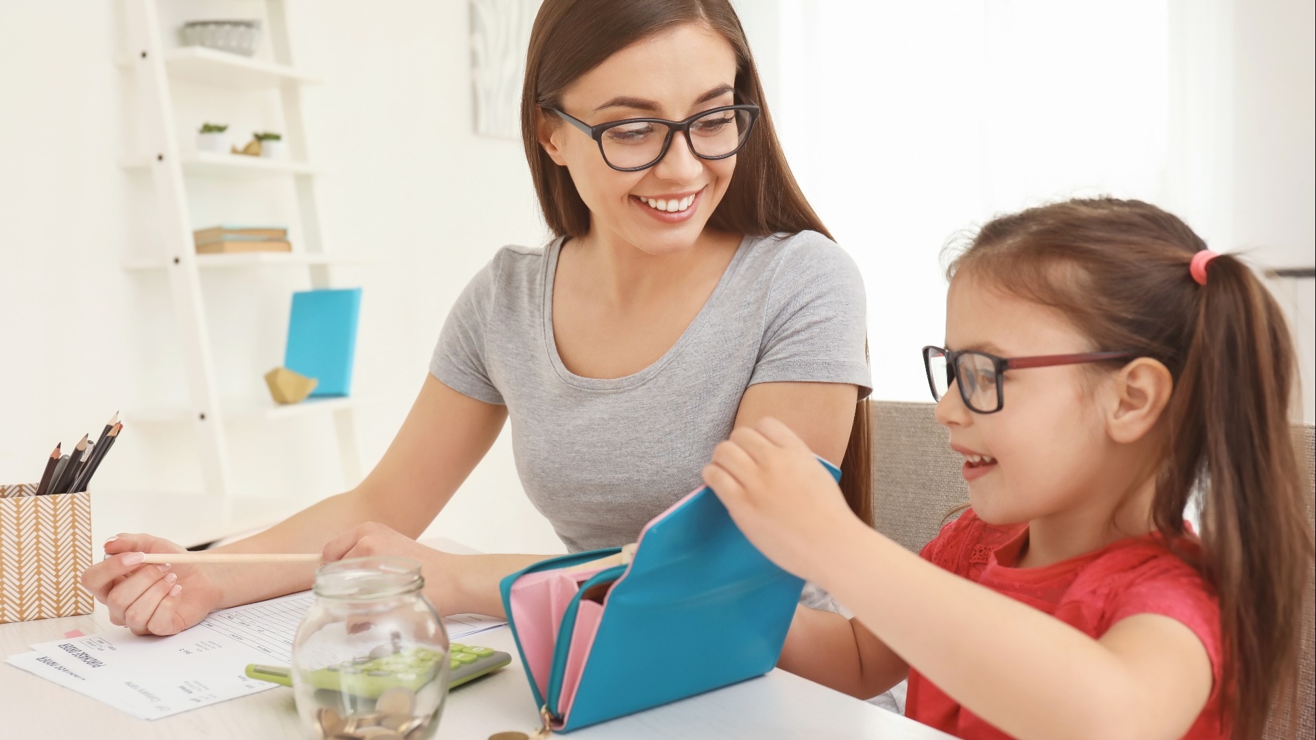 Happy little girl with her mother sitting at table and counting