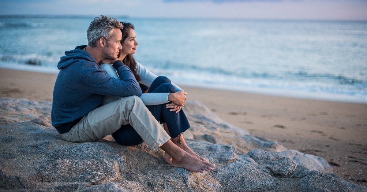 couple sitting at the beach watching the sunset