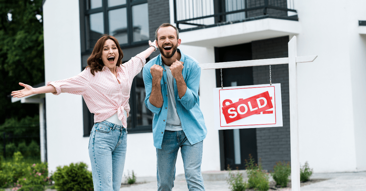 Happy couple outside sold house