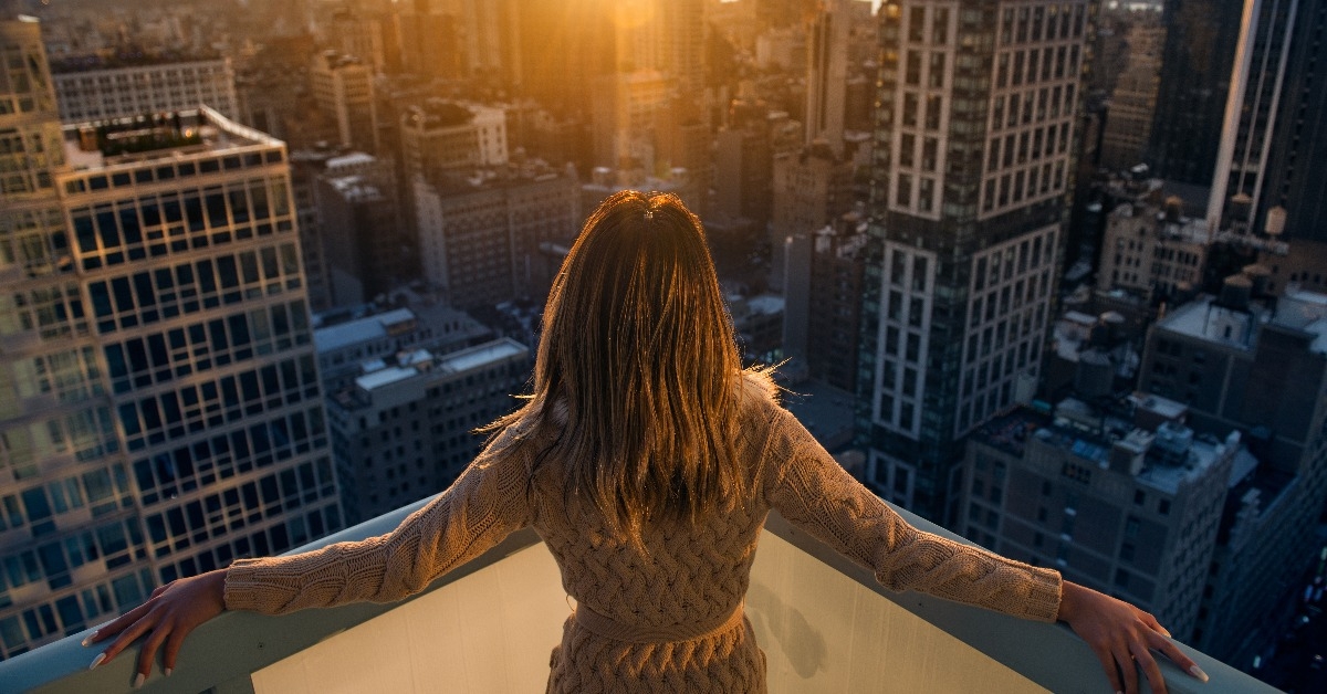 Rich woman enjoying the sunset standing on the balcony of a luxury apartments in New York City