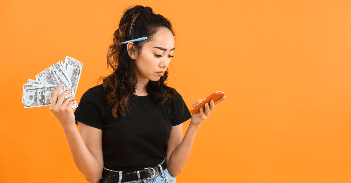 Woman holding cash and looking at phone