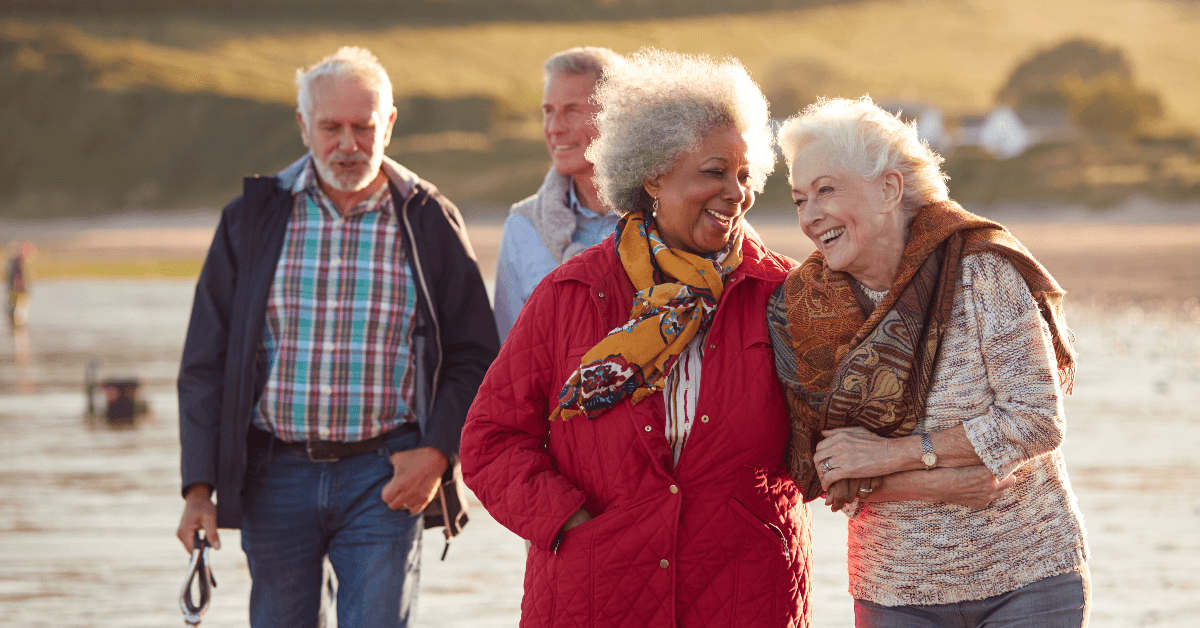 Retired friends walking on beach