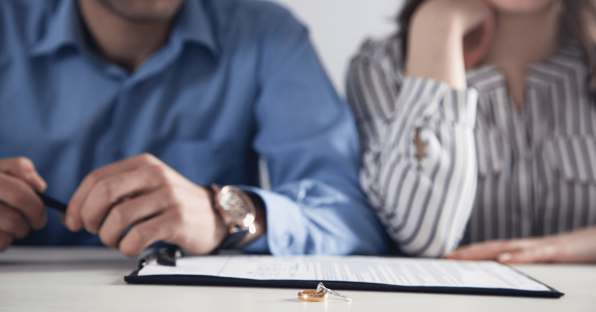 Couple with divorce contract and rings on desk