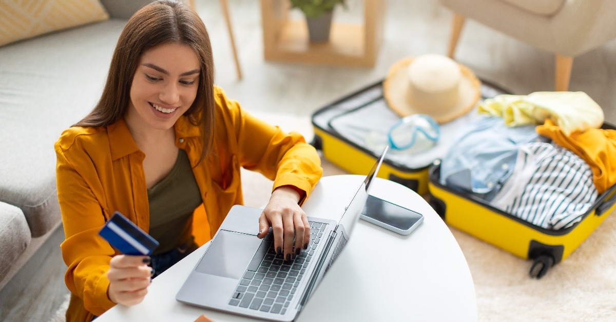 Happy young woman with credit card booking vacation at travel agency