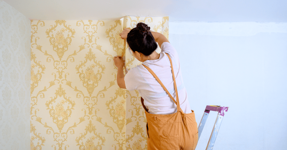 Woman taking wallpaper off wall in house