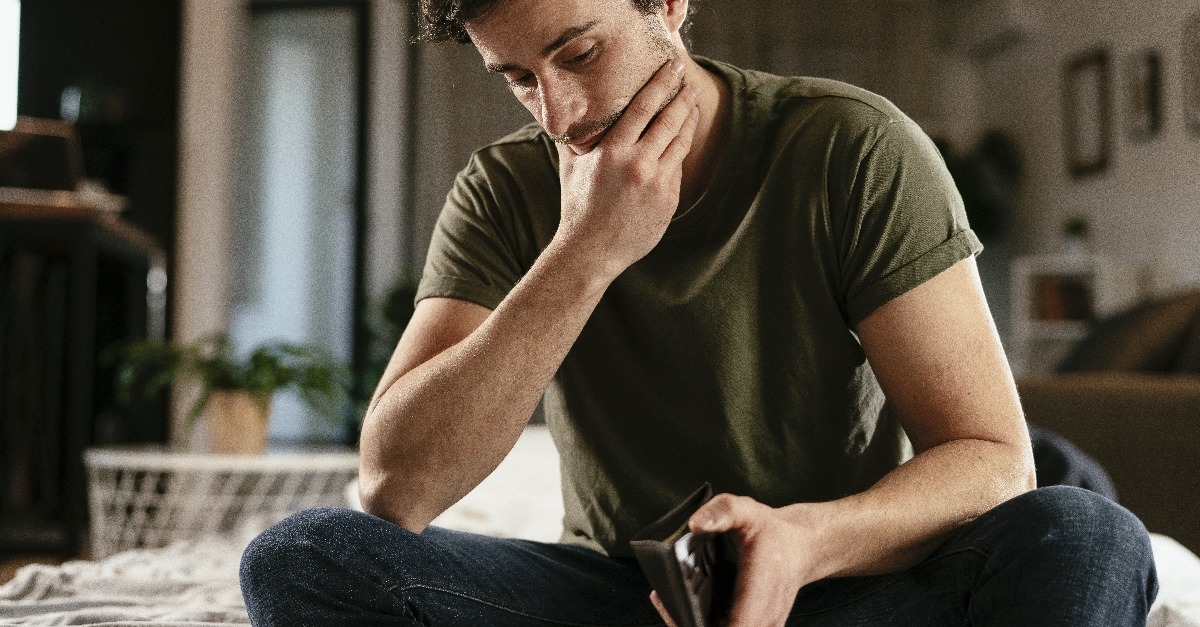 unemployed sad man sitting at home thinking about money