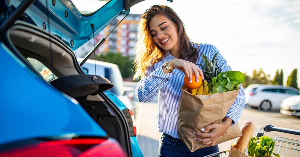 young woman with groceries at parking lot