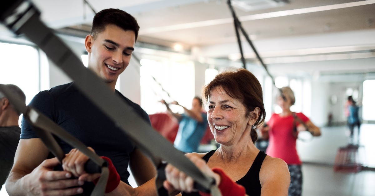 group of cheerful seniors in gym with a young trainer 
