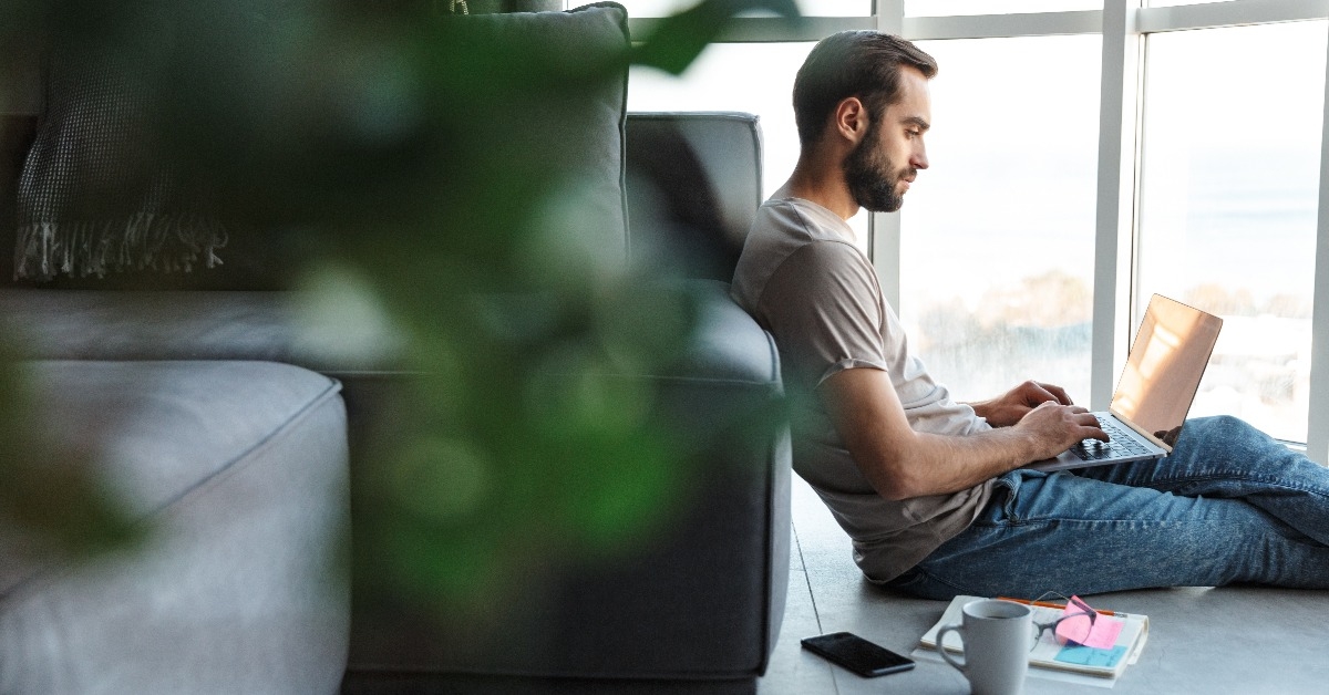 concentrated young man using laptop computer sitting on the floor