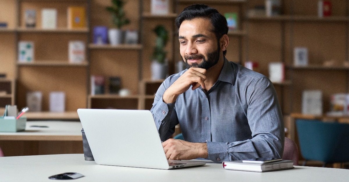 smiling bearded indian businessman working on laptop