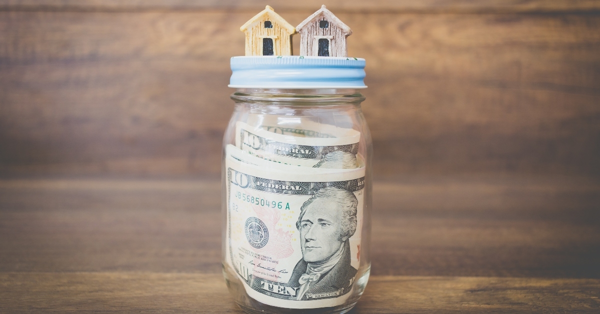 Jar of money with tiny house figurines on top