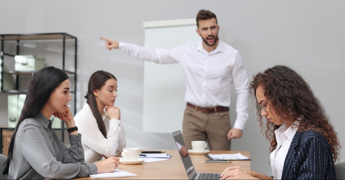 man screaming at African American woman in office