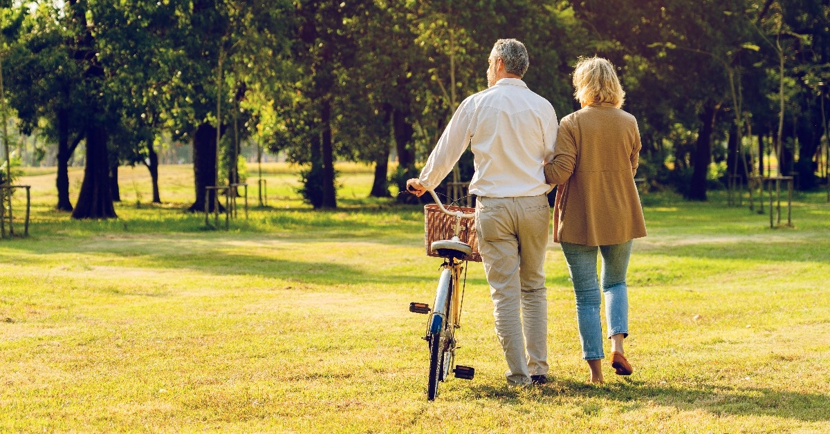 elderly couple walking while holding a bike
