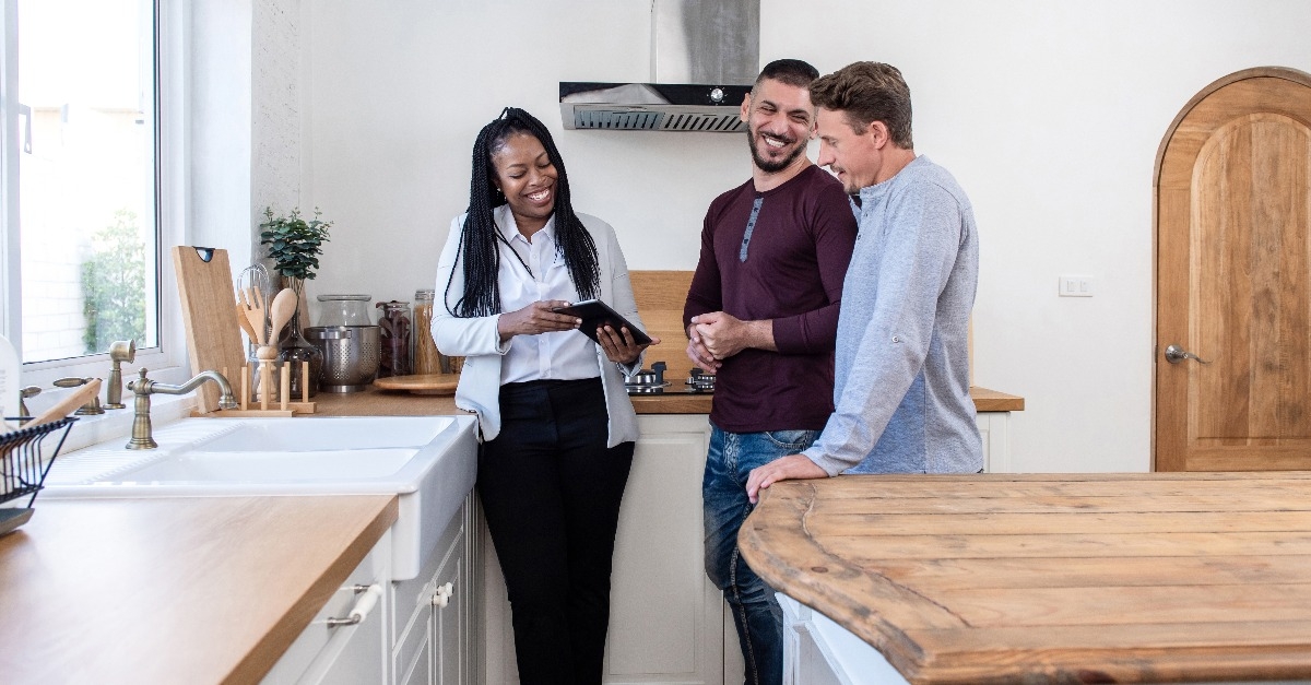 female real estate agent showing gay couple around new house