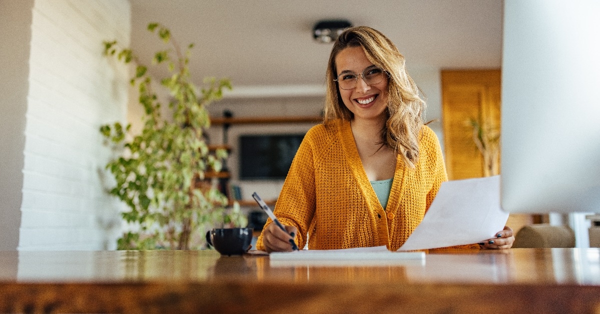 smiling adult woman writing on documents