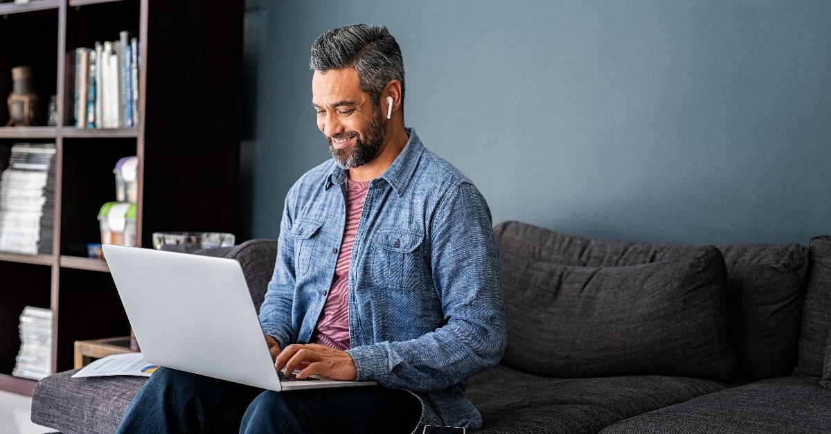 Indian man typing on laptop while working from home