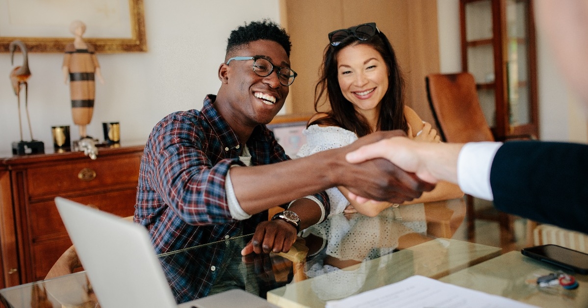couple handshaking realtor after signing contract