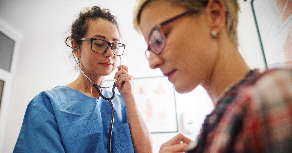 female middle-aged doctor using stethoscope to examine patient