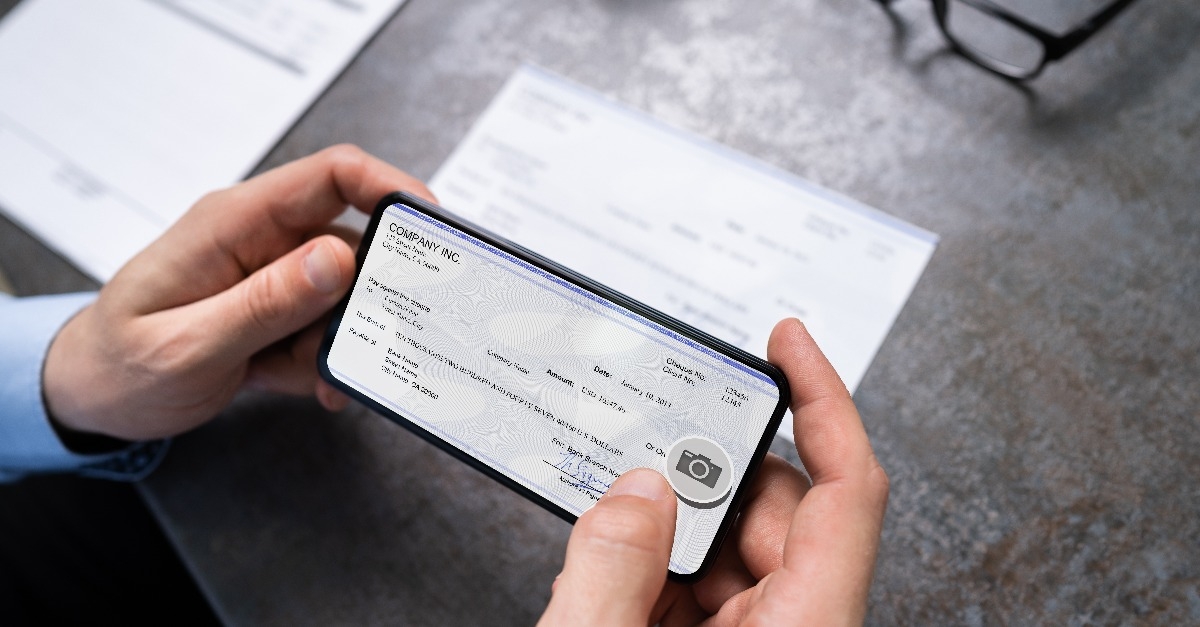 man taking photo of cheque to make remote deposit