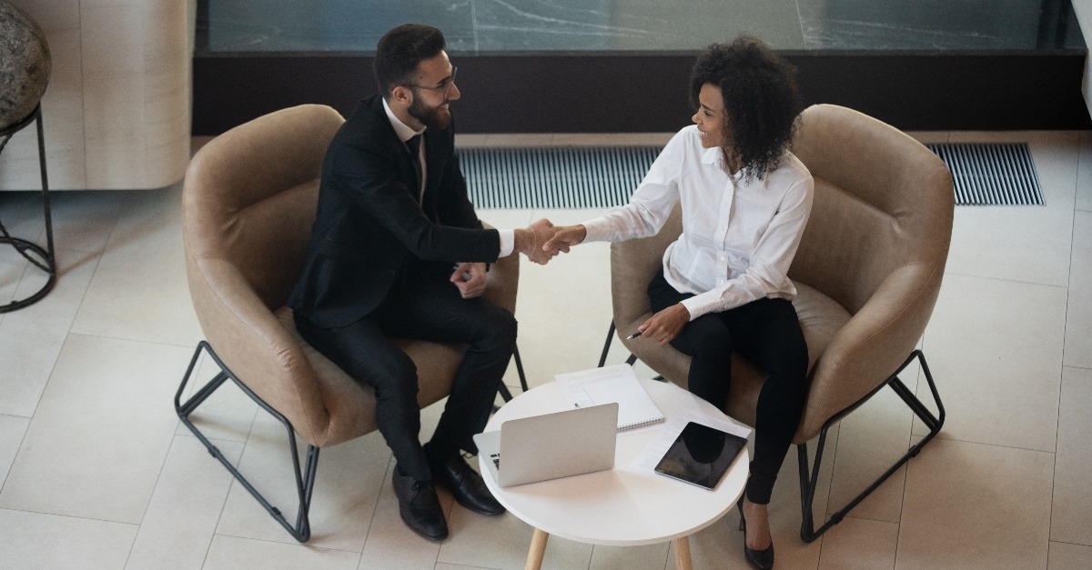 businesswoman shaking hands sit on armchairs indoors