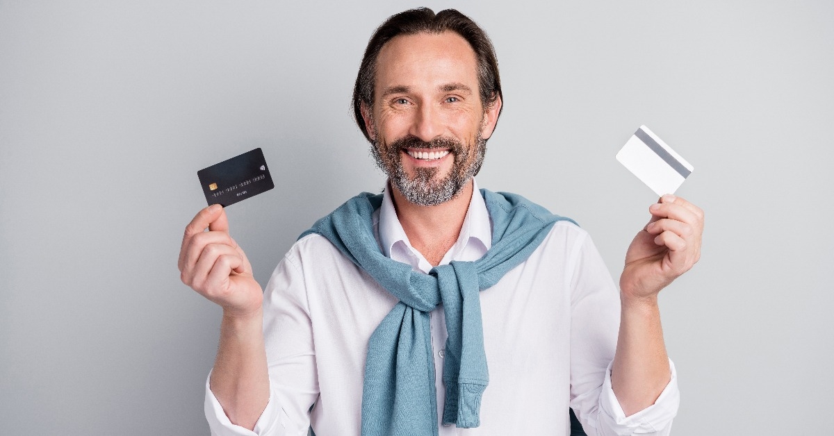 smiling businessman in white shirt showing plastic bank credit cards 