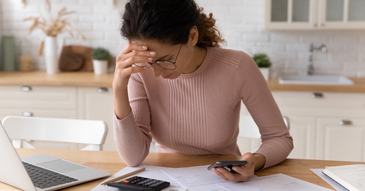 Latina woman sitting in kitchen checking personal finances