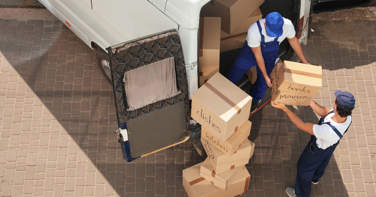 male movers unloading boxes from van outdoors