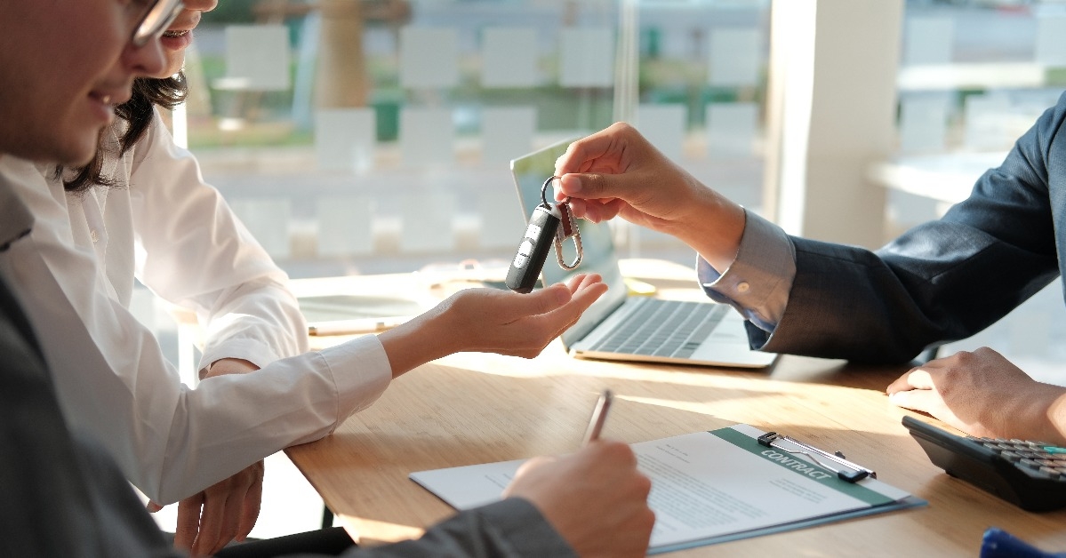 dealer salesman giving car key to owner