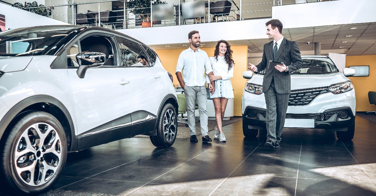 sales manager helping young couple to choose a new car