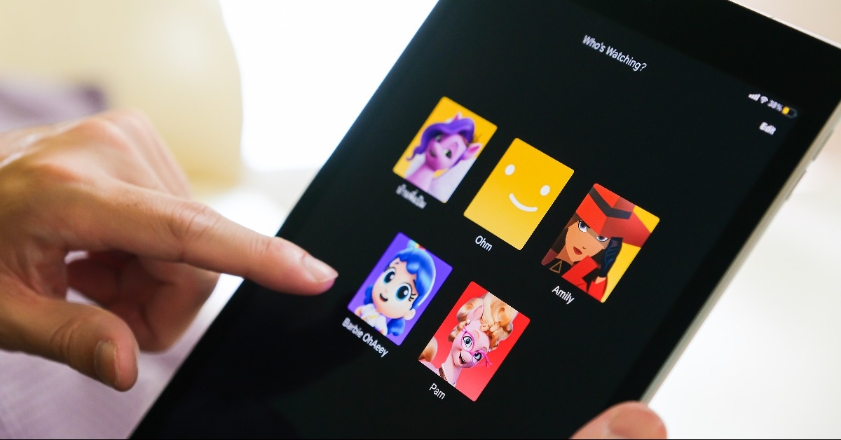 hand while using remote control to select user to watch Netflix 