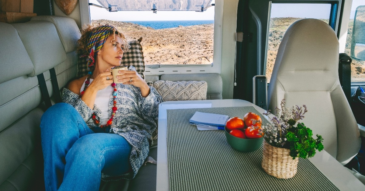 adult woman laying on the sofa inside her cozy alternative home camper van
