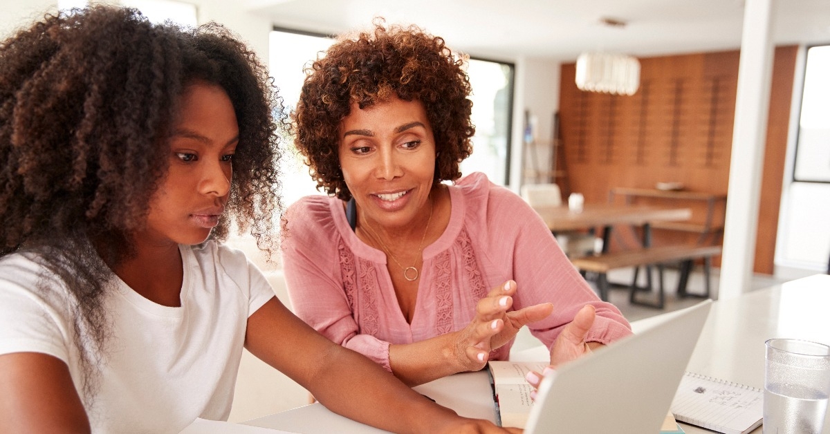 middle aged black woman helping her teenage daughter with homework