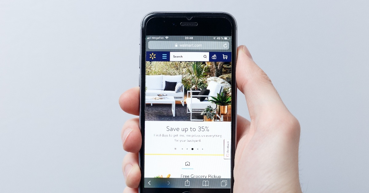 hand holding a smartphone which displays Walmart logo