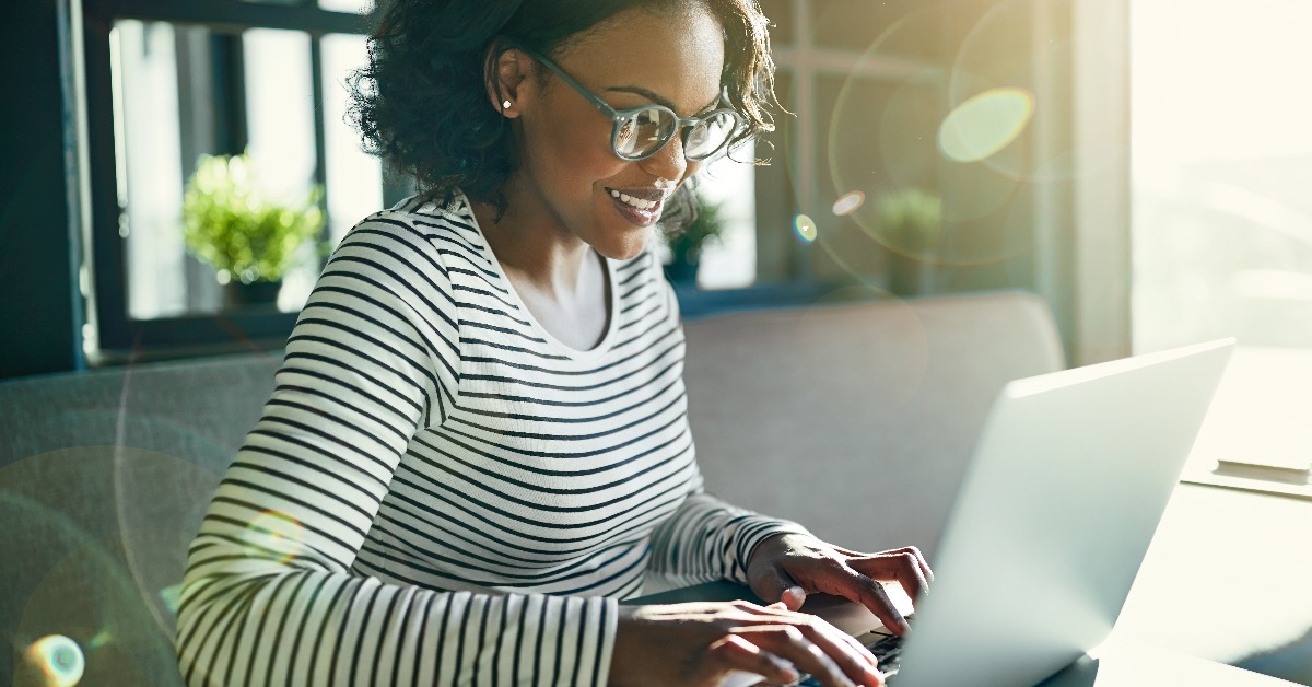 African woman smiling and working online with a laptop