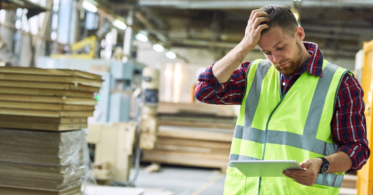 factory worker wearing reflective vest filling out shipping notice