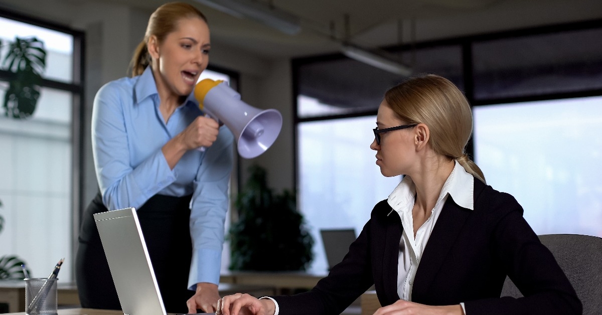 Lady boss shouting with megaphone at colleague