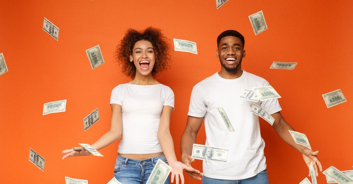 Young black couple standing under money banknotes shower