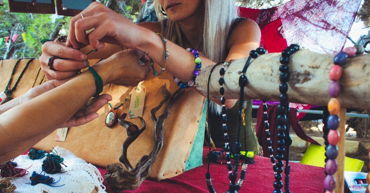  woman selling homemade craft jewelry from a market stall