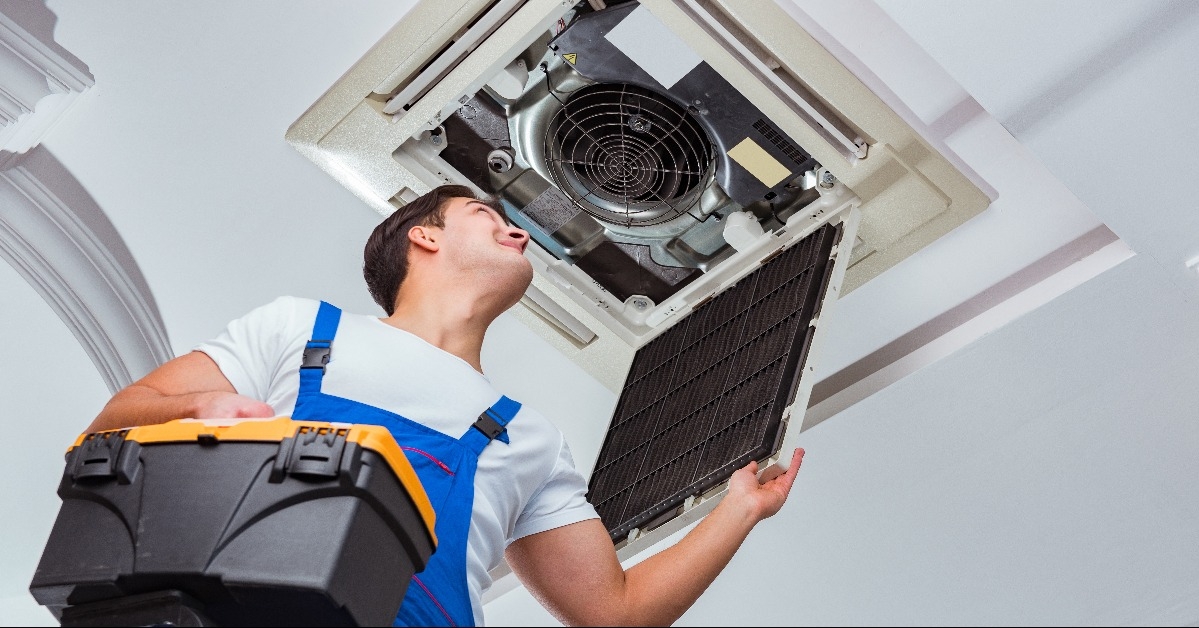 Worker repairing ceiling air conditioning unit