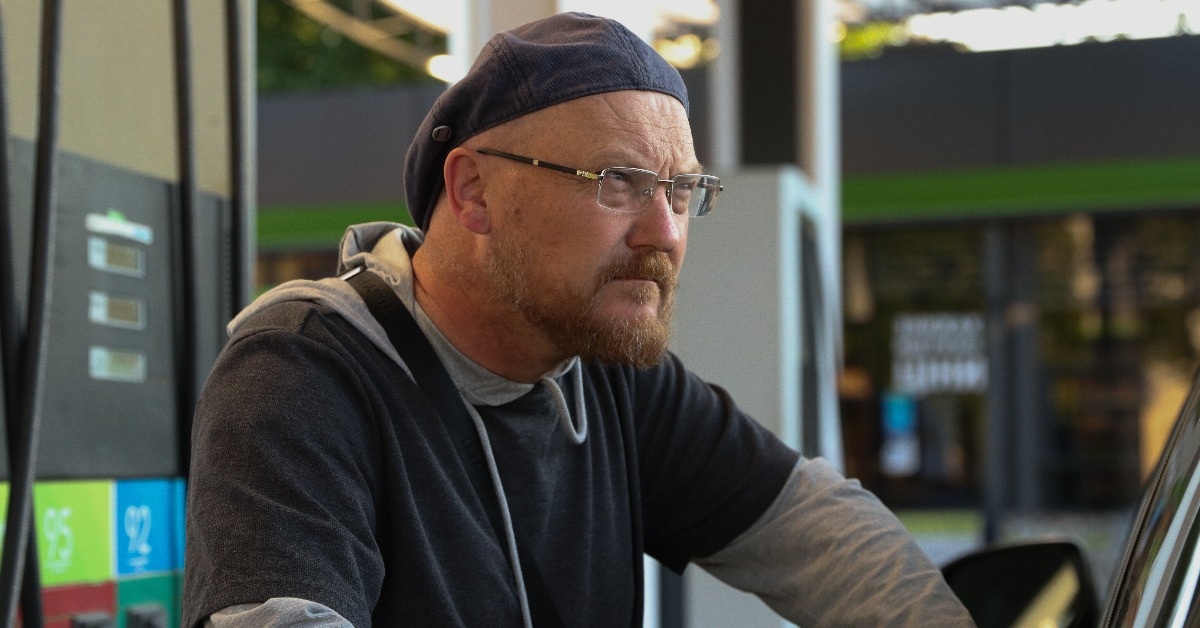 Traveling man pumps gas into his car on a gas station