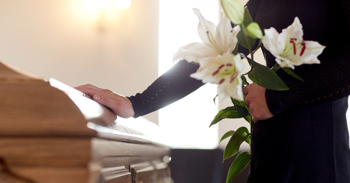 woman with lily flowers and coffin at funeral