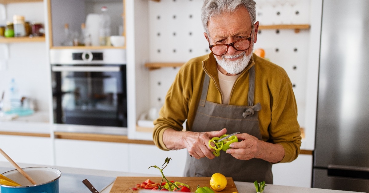 Mature handsome man cooking in home kitchen