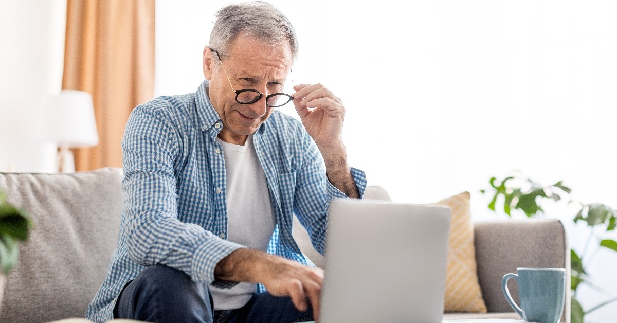 mature man squinting using laptop