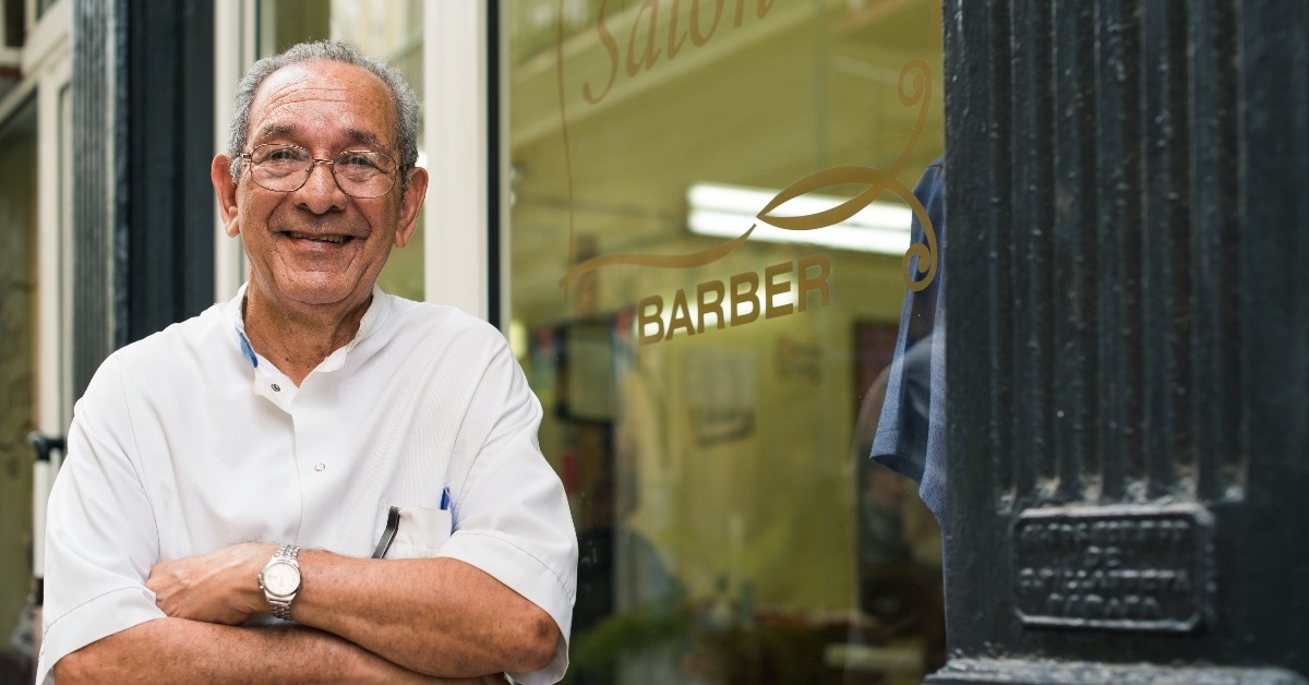 portrait of old barber smiling in hair salon